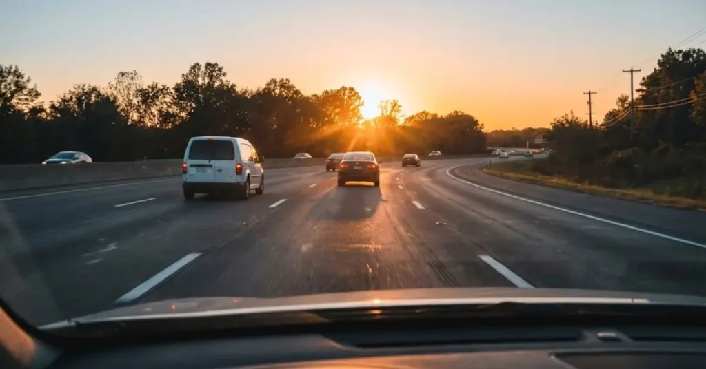 Multi-lane highway with vehicles driving toward sunset during evening traffic