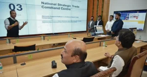 Officials attending a trade command centre presentation, with the National Strategic Trade Command Centre displayed on a large screen in a conference room.