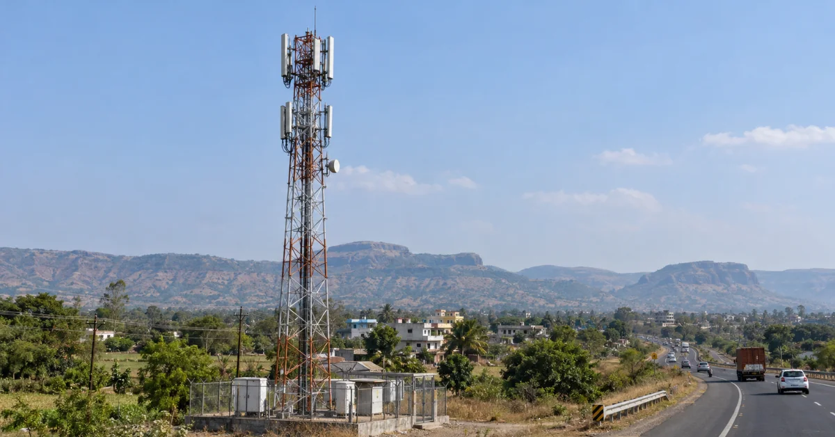 Documentary-style view of a telecom tower beside a Nashik-region highway, providing context for BSNL's plan for 211 new towers.