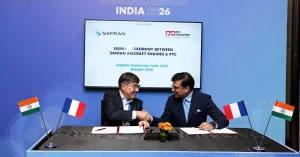 Representatives of Safran Aircraft Engines and PTC Industries shake hands during an MoU signing ceremony, with Indian and French flags displayed on the table.
