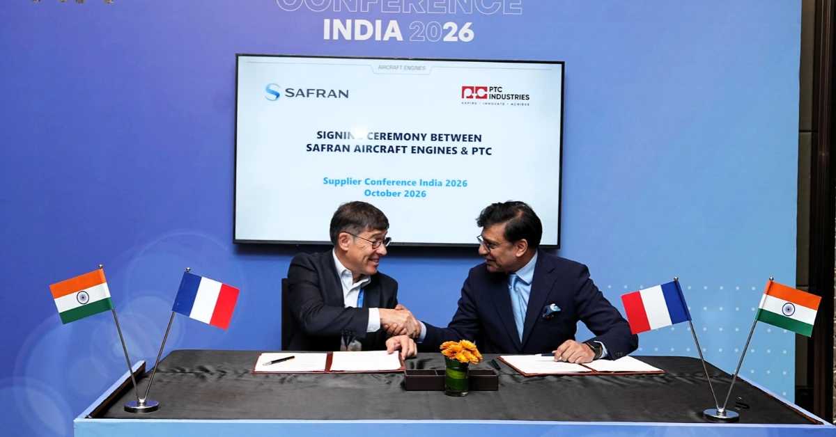 Representatives of Safran Aircraft Engines and PTC Industries shake hands during an MoU signing ceremony, with Indian and French flags displayed on the table.